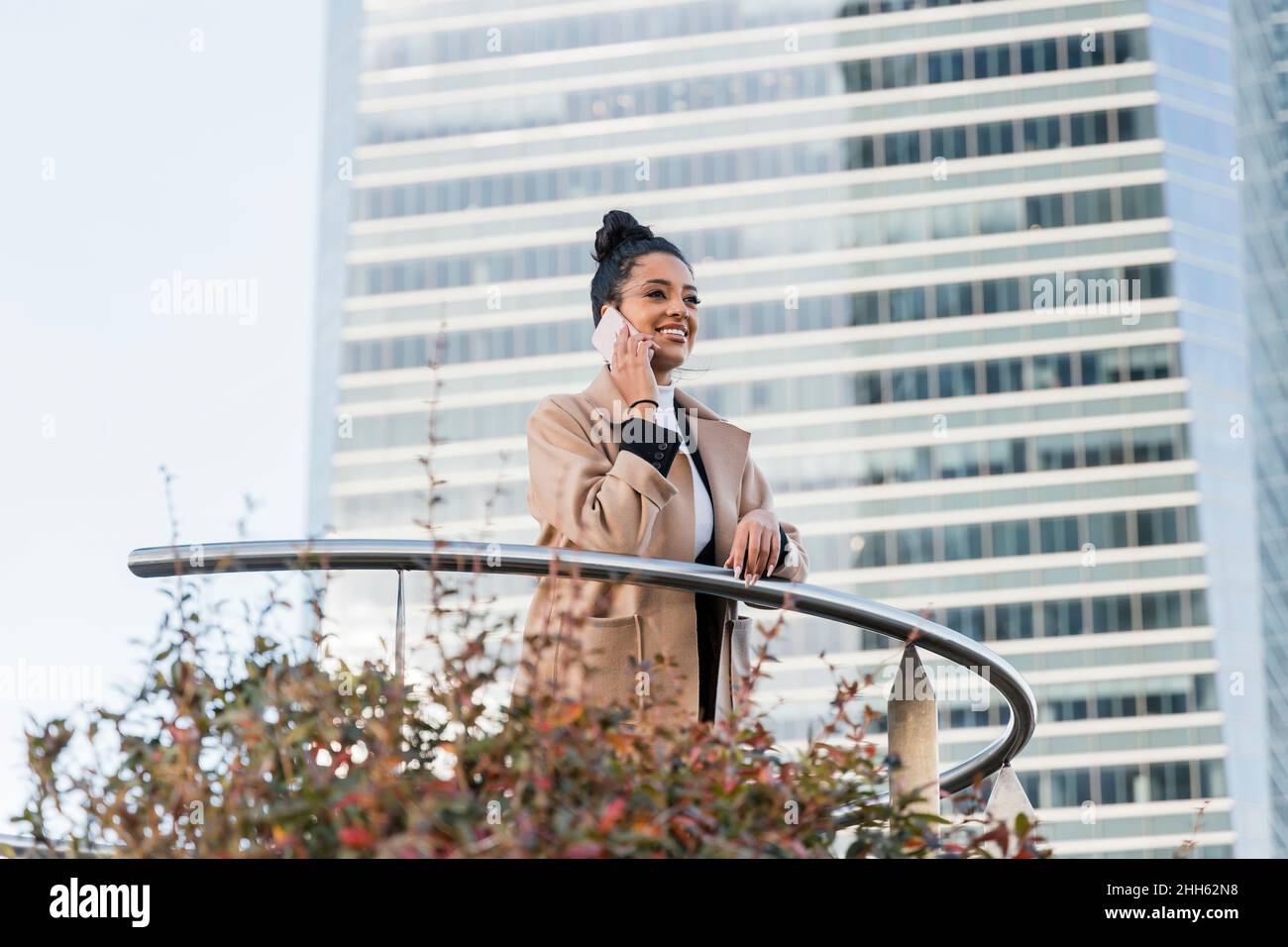 Smiling freelancer talking on mobile phone by railing Stock Photo