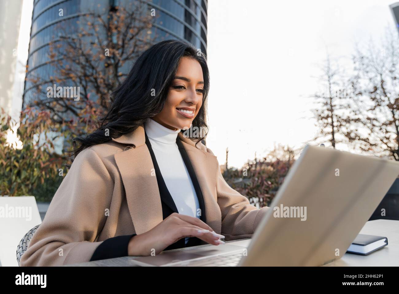 Smiling young freelancer using laptop working at table Stock Photo