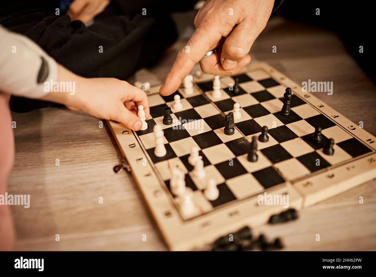 Grandfather pointing at girl holding chess piece Stock Photo