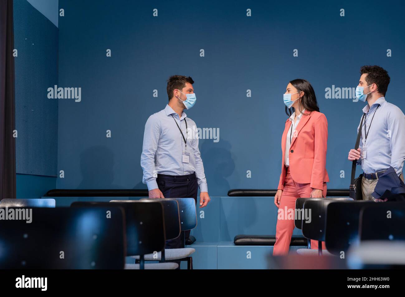 Colleagues with protective face mask talking in board room at conference Stock Photo