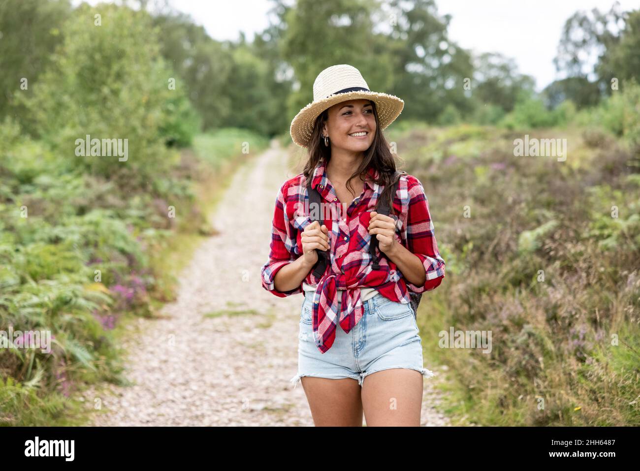 Smiling woman with hat walking on footpath at Cannock Chase Stock Photo