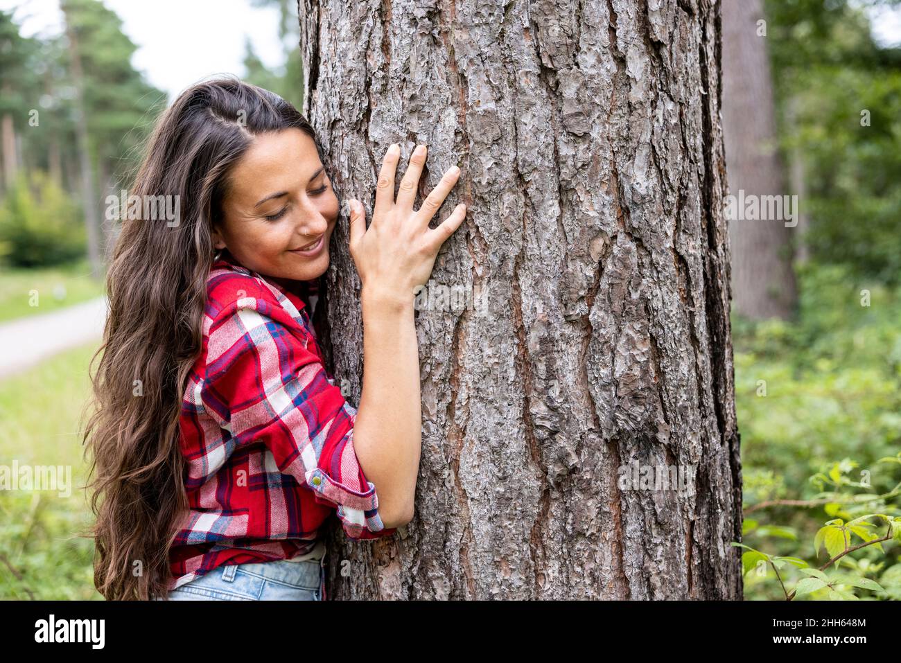 Smiling woman embracing tree at Cannock Chase Stock Photo