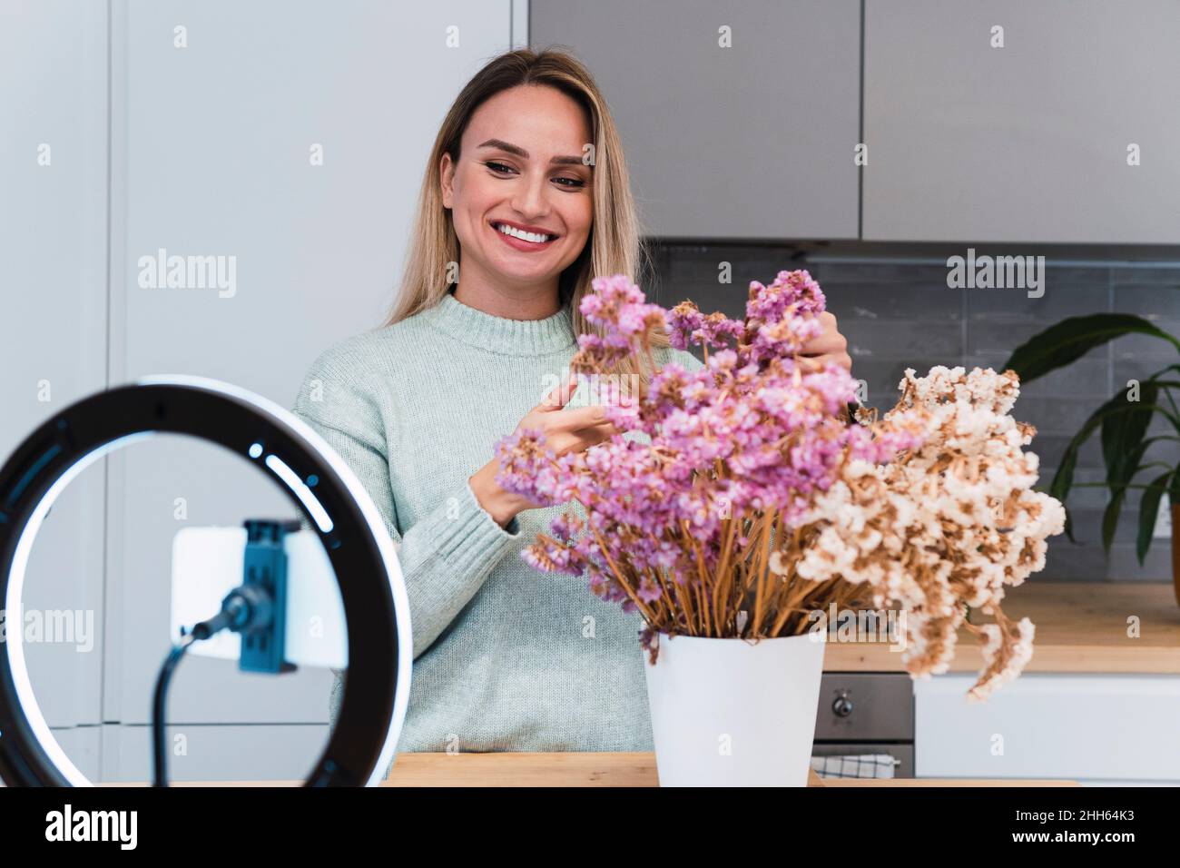 Influencer with potted plant filming tutorial at home Stock Photo