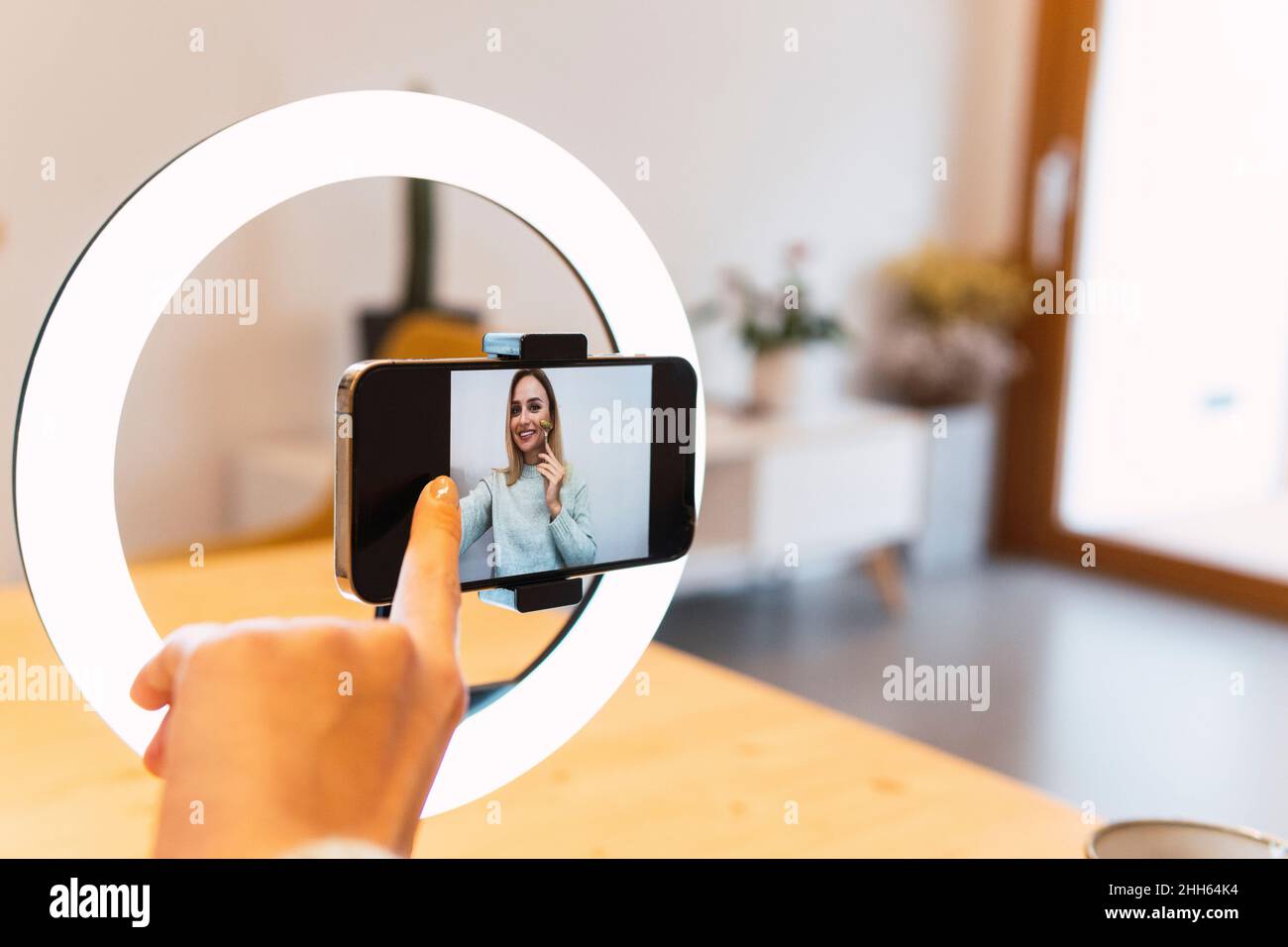 Influencer touching phone screen attached on ring light Stock Photo