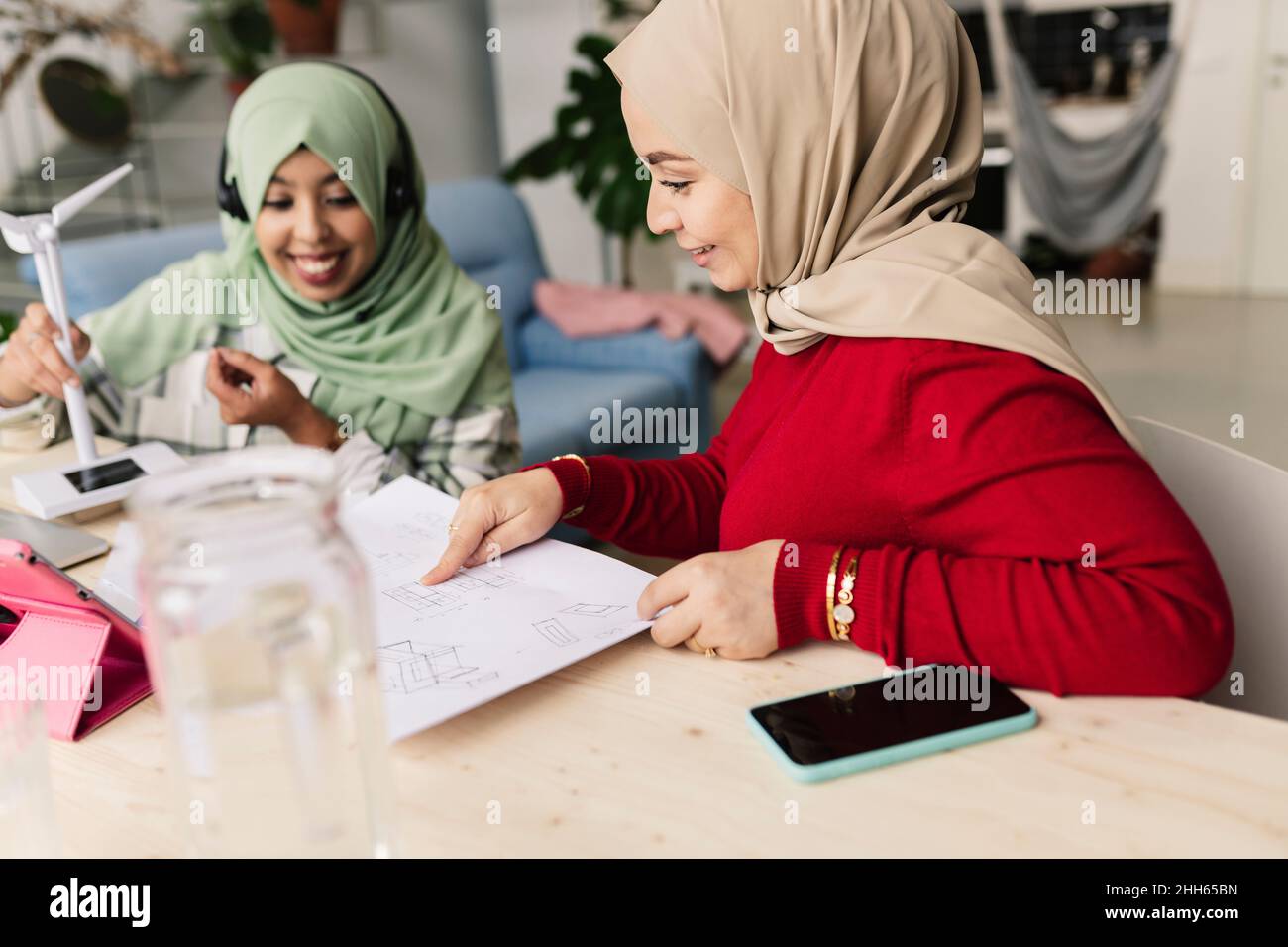 Happy colleagues discussing over document at home Stock Photo