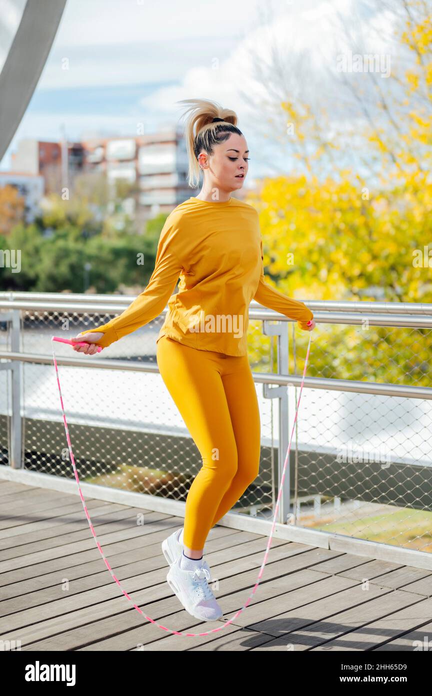 Determined young athlete exercising with jumping rope on bridge Stock Photo