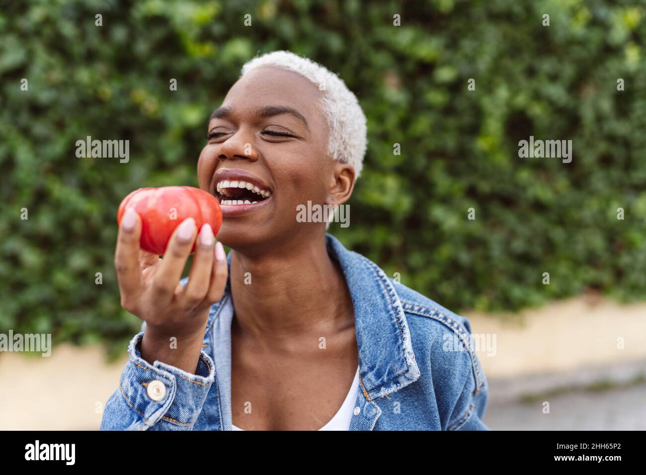 Young woman laughing holding tomato in hand Stock Photo - Alamy