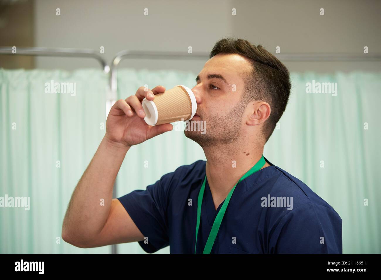 Male nurse drinking coffee in disposable cup at hospital Stock Photo