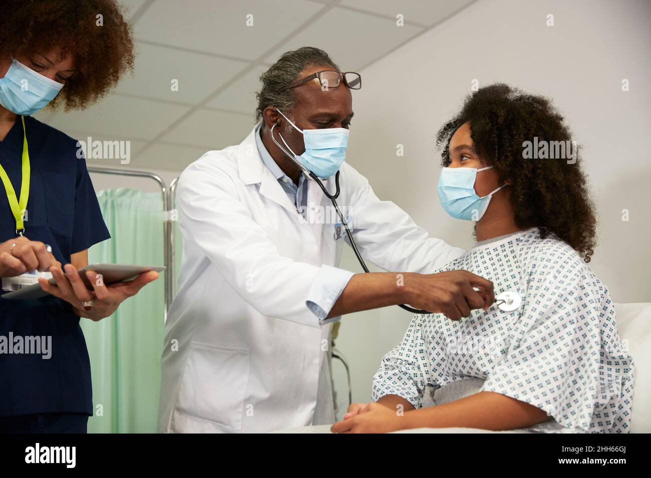 Doctor examining patient standing with female nurse in medical room Stock Photo
