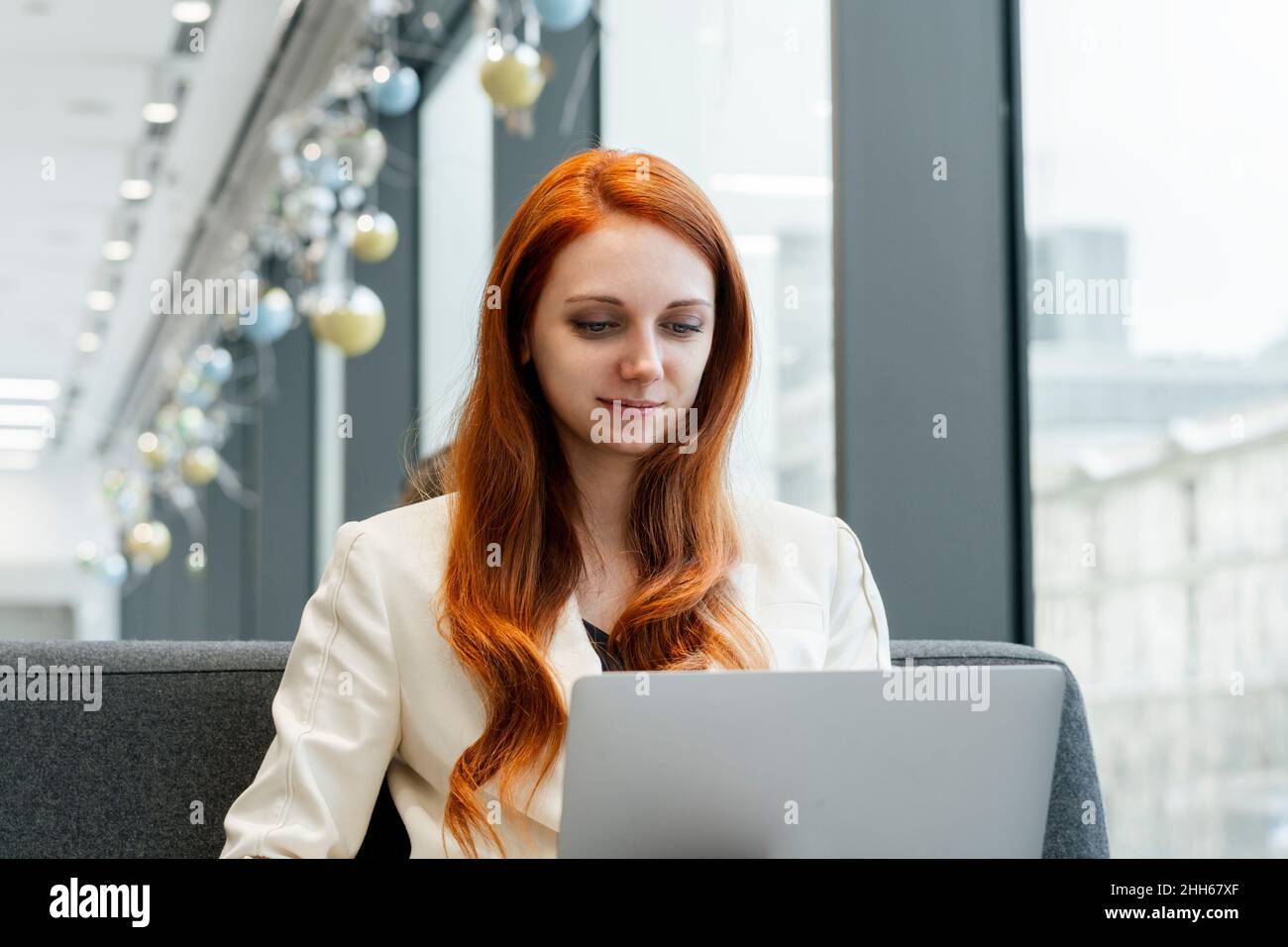 Redhead businesswoman using laptop in cafeteria at workplace Stock ...