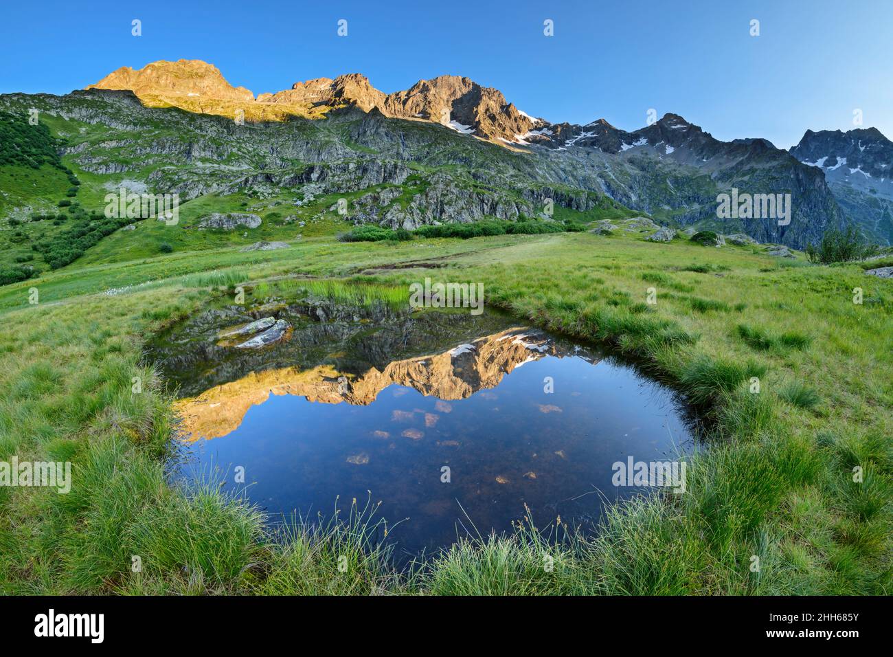 Reflection of mountain range and blue sky in sea eye puddle, Valgaudemar, Ecrins National Park, France Stock Photo