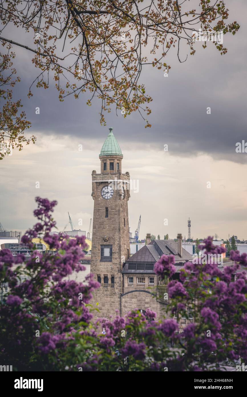 Germany, Hamburg, Clock tower in Saint Pauli Piers with blooming flowers in foreground Stock Photo