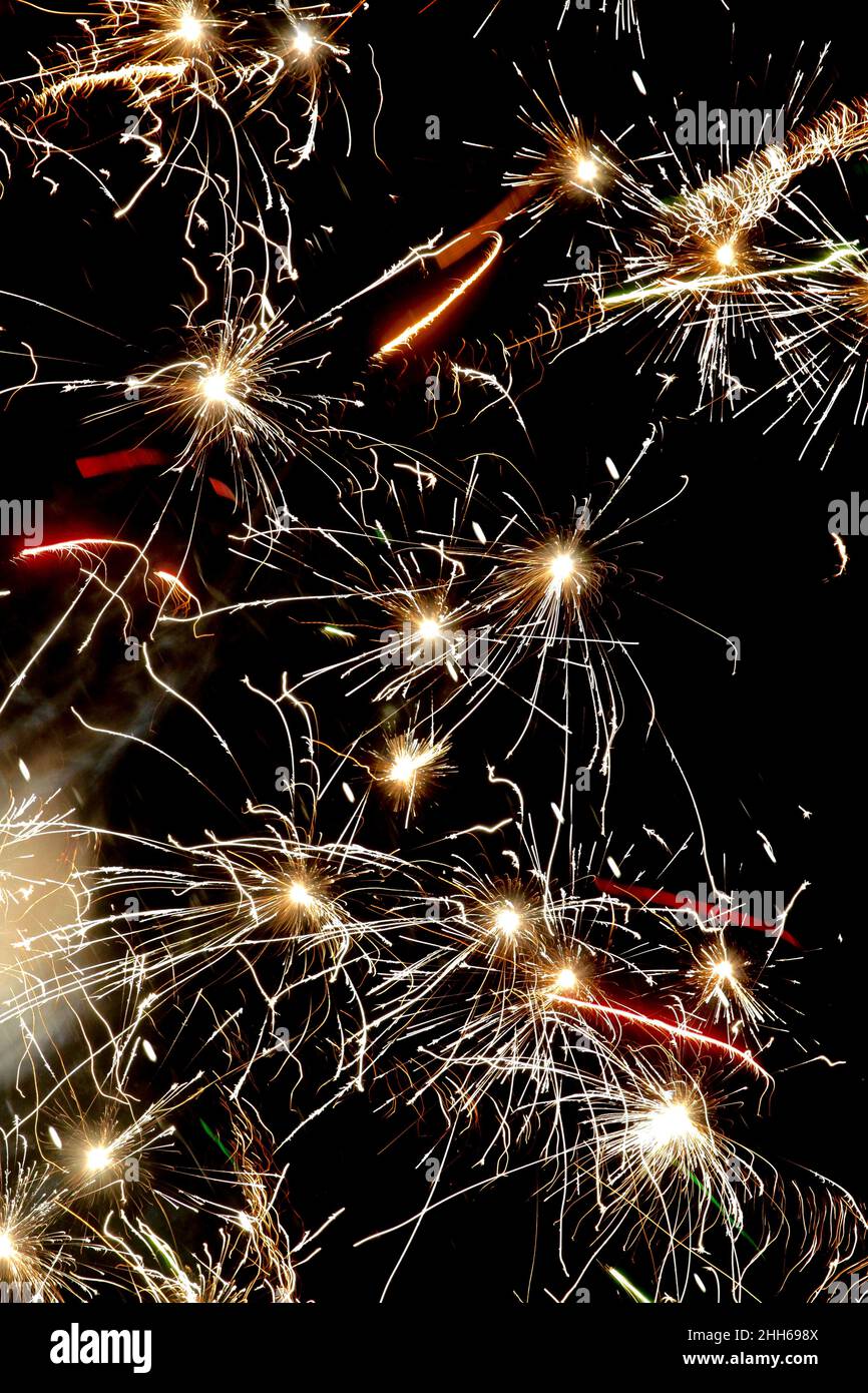 Yellow fireworks exploding against clear night sky Stock Photo