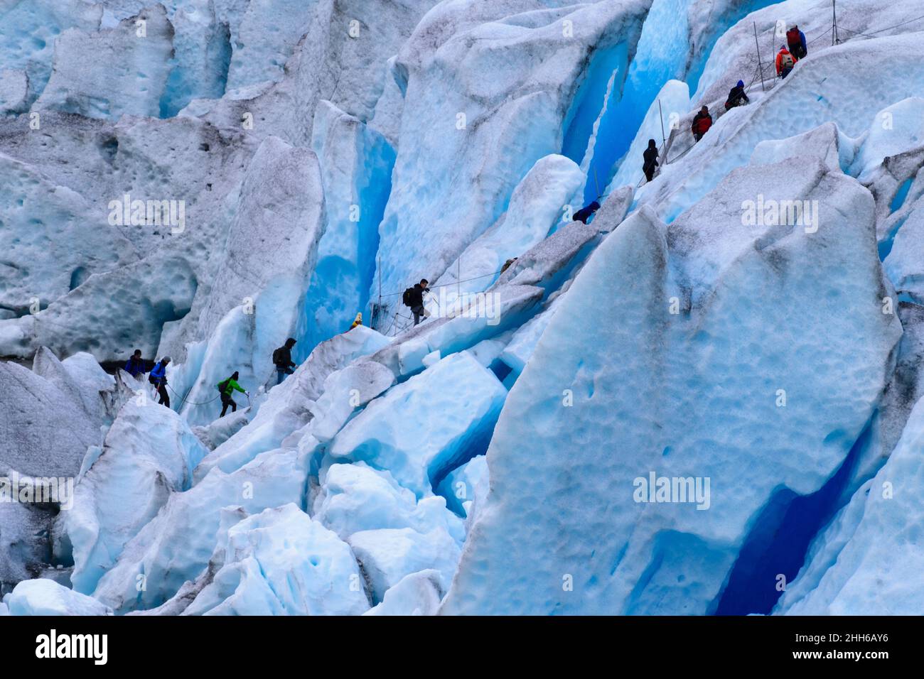 Hikers climbing over crevasses on Nigardsbreen Glacier, Norway. Stock Photo