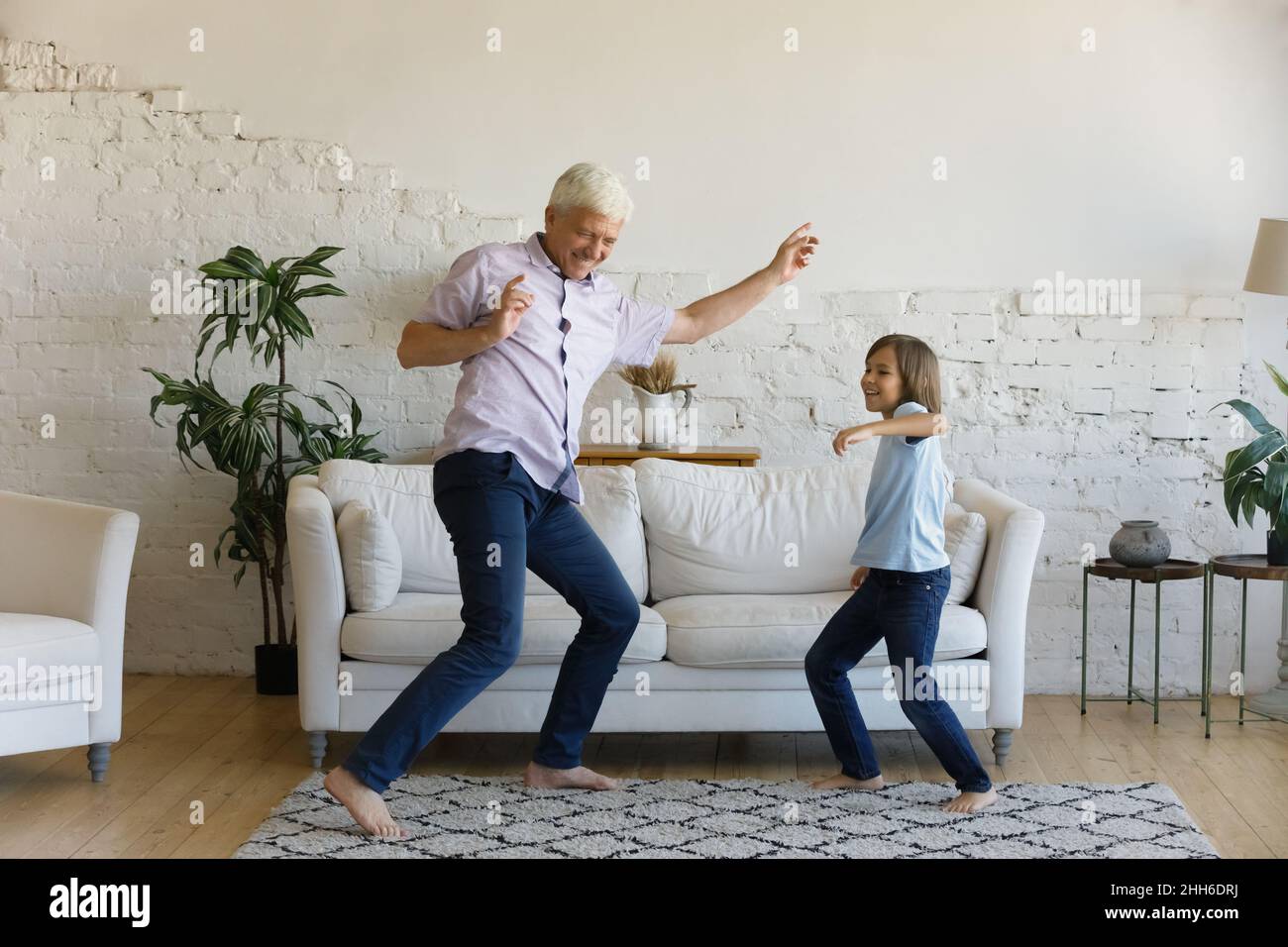 Happy active grandpa and cheerful grandkid dancing to music Stock Photo