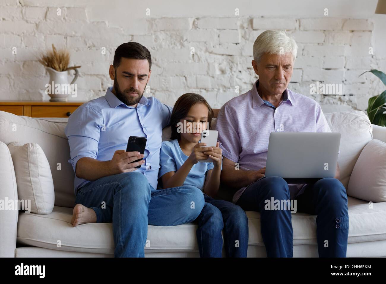 Digital addicted three male family generations using devices at home Stock Photo