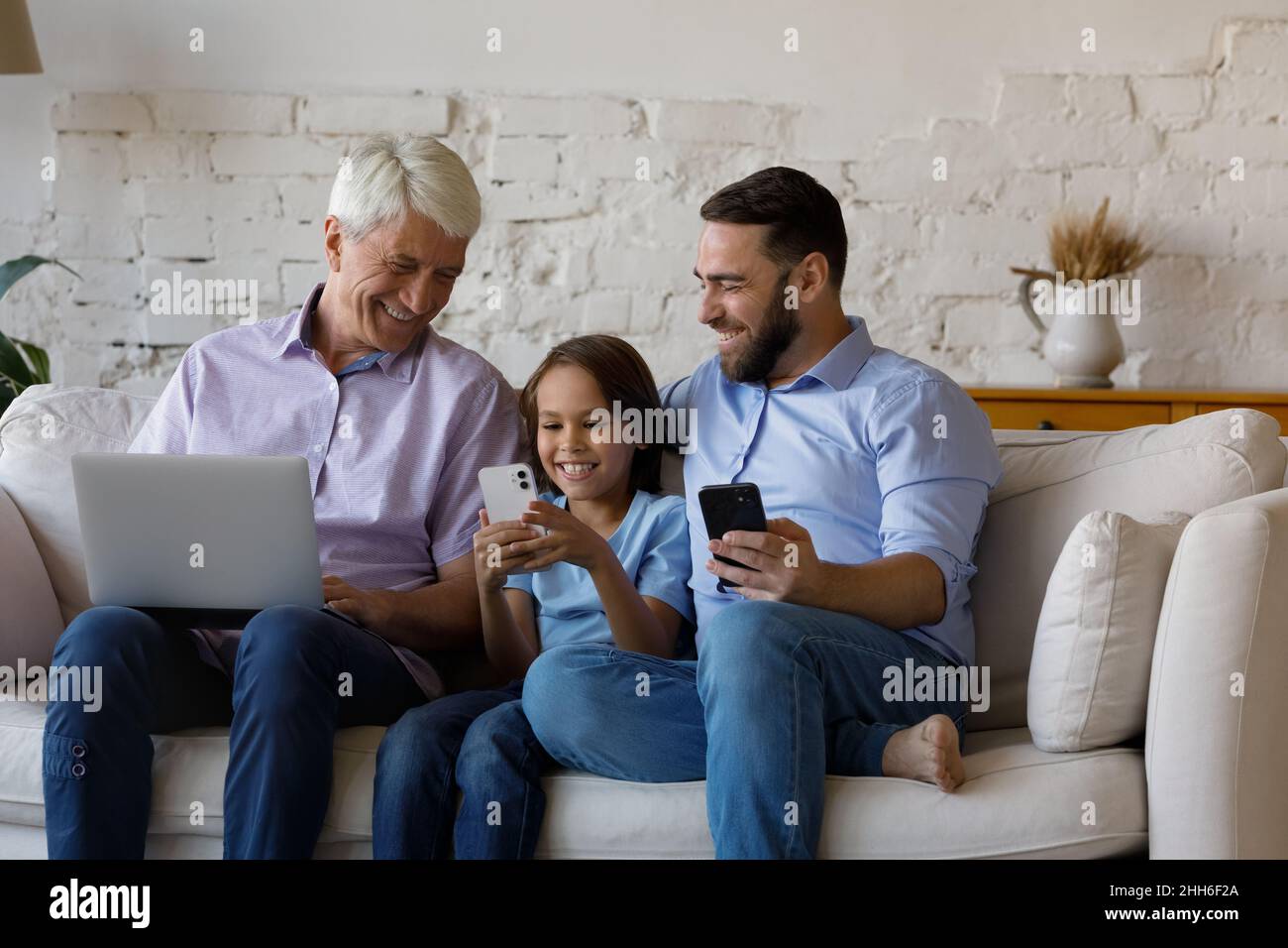 Happy kid, dad, grandpa using digital gadgets at home Stock Photo