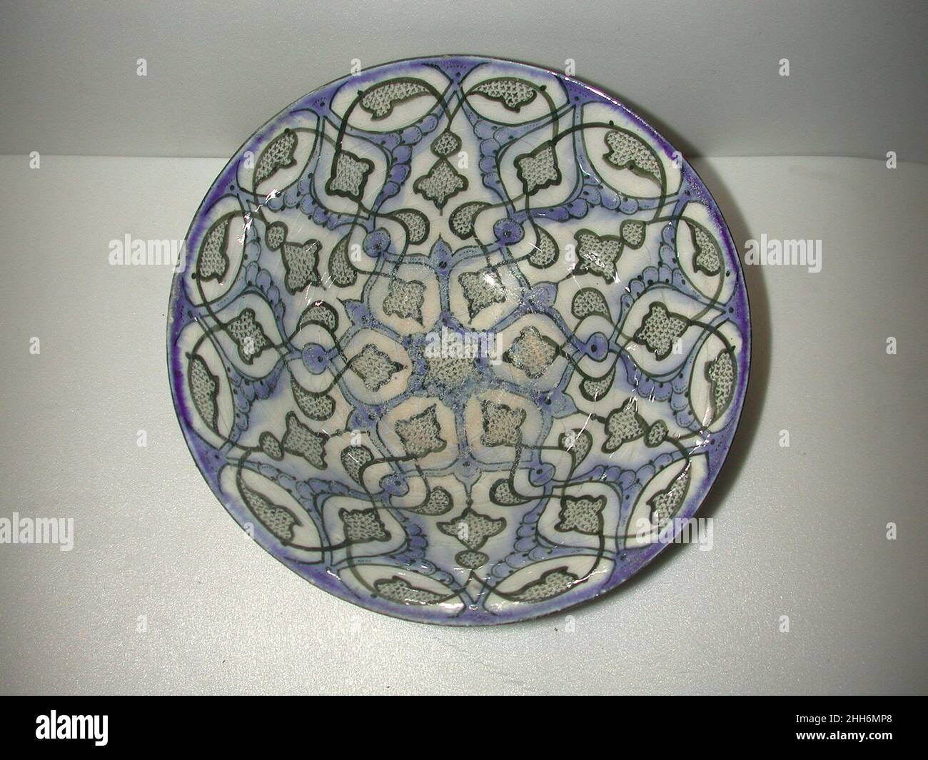 Black and Blue Painted Bowl early 13th century The whiteness of stonepaste provided a canvas upon which potters could paint pigments directly, rather than applying a slip. By the early thirteenth century, a new type emerged, decorated in black and blue against the white ground, usually with vegetal motifs inside radial frameworks. The stable black pigment creates crisp outlines and fine details, while the rather runny blue fills contours and highlights forms. Underglaze painting would have long‑term consequences on the development of Iranian ceramics.. Black and Blue Painted Bowl  451767 Stock Photo