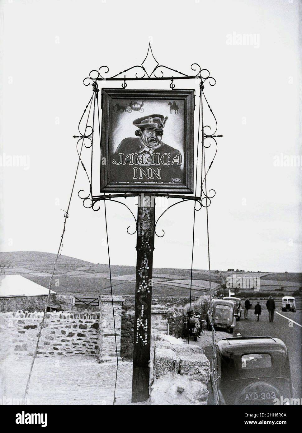 1950s, historical, Sign for the Jamaica Inn, an historic smugglers pub on Bodmin moor, Bolventor, Cornwall, England, UK, with cars of the era parked roadside. Built in 1750, this old coaching inn is immortalised in writer Daphne du Maurier's famous novel of the same name. Stock Photo
