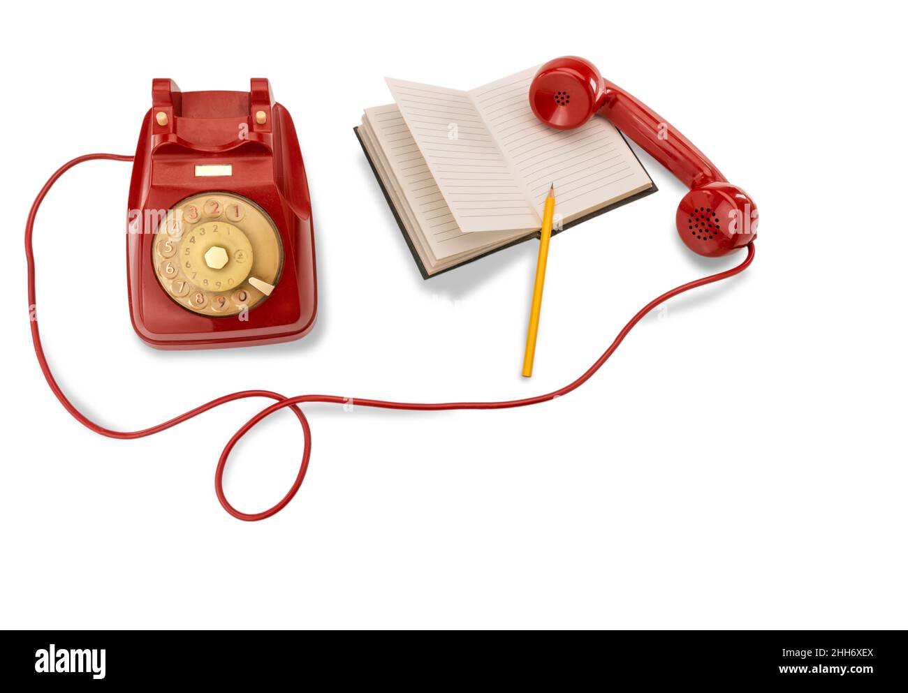 Old red rotating dial telephon with lined notebook and yellow pencil in top view isolated on white background, copy space Stock Photo