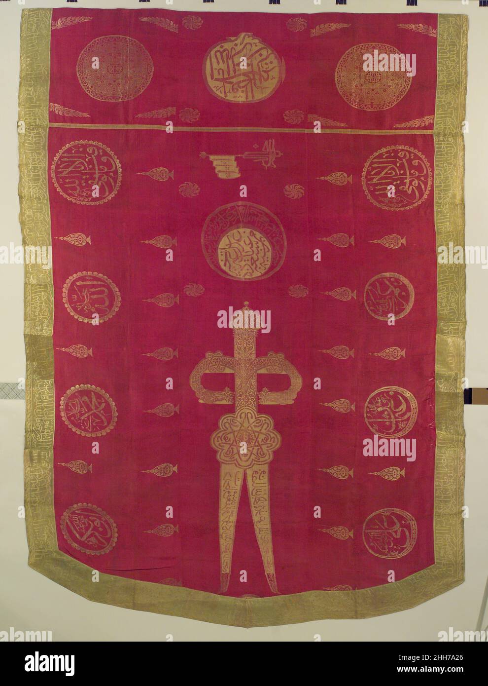 Banner dated A.H. 1235/ A.D. 1819–20 Inscribed with the names of God, the Prophet Muhammad and the first four leaders of the Muslim community, and bordered by Qur'anic verses, this silk sanjak (shield-shaped banner) displays an image of a two-bladed sword with a dragon-headed hilt. Referred to as Dhu'l Fiqar and associated with military victory, this sword is said to have belonged to 'Ali, the cousin and son-in-law of the Prophet. While Ottoman banners similar to this one were used as military insignia from the 15th century onward, this example bears an early 19th century date, and may have be Stock Photo