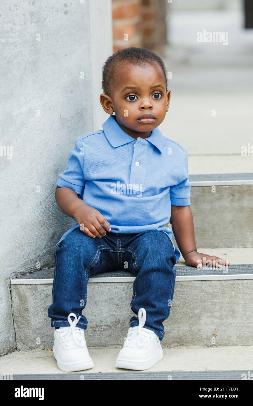 A cute one year old toddler almost preschool age African-American boy with big eyes smiling and looking away Stock Photo