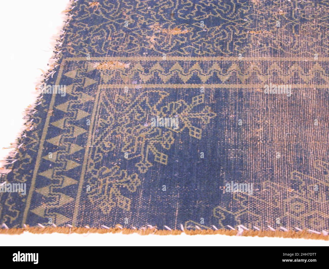 Carpet Fragment 16th century This fragment depicts a variety of vegetal forms, including scrolling leaf and vines along the border, as well as a popular blossom or pomegranate-style design inside an alternating pyramidal merlon border.. Carpet Fragment  451462 Stock Photo