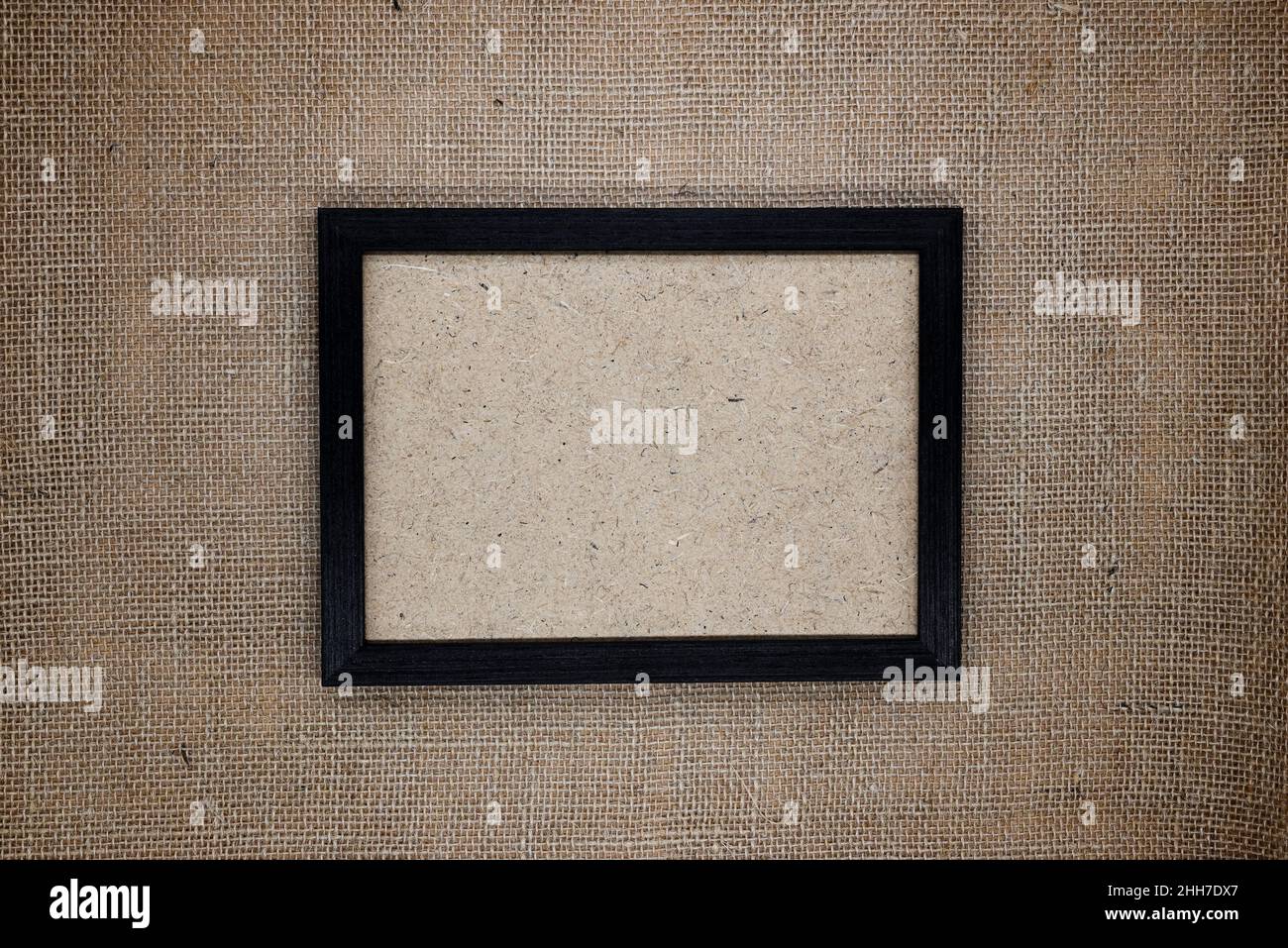 Mockup, сomposition from natural materials, eco concept. Dark brown wooden frame on burlap. Inside the frame is a wooden fiber base. Stock Photo