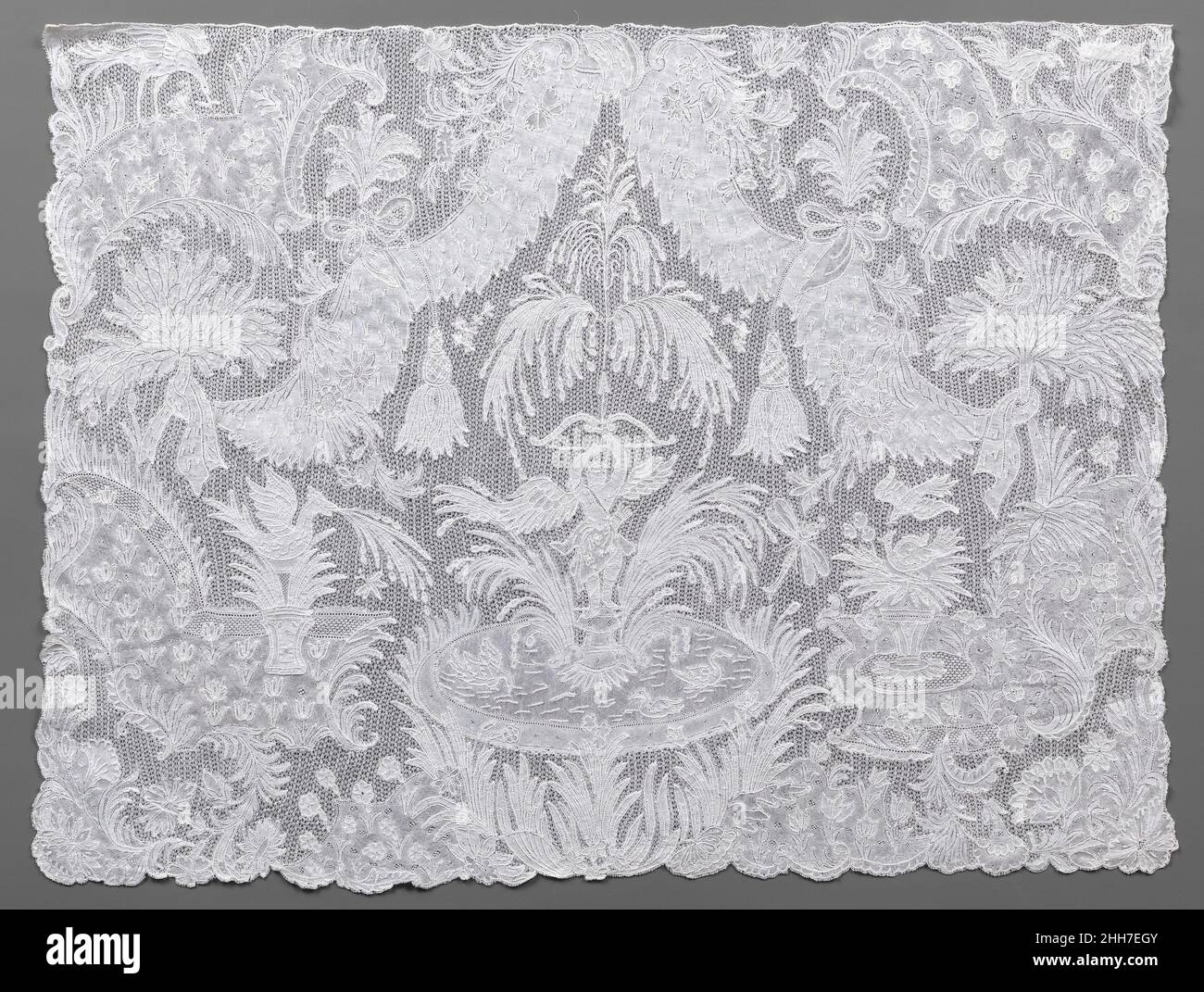 Cravat end mid-18th century Flemish, Brussels Figural lace panels such as this one were items of gentlemen's high-fashion neckwear, meant to be attached to the end of a long, fine fabric cravat. The elaborate imagery, time-consuming to achieve, made the panels extremely expensive accessories. Drawing inspiration from contemporary formal gardens, the design of this example centers on a fountain with water jets that issue from the tip of Amor's raised arrow and fall to fill a basin for swimming birds. Set among the parterres planted with tulips and other flowers is a fountain in the form of the Stock Photo