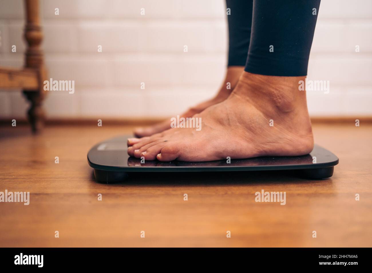 Detail of Woman weighing herself on a bathroom scale. Diet problems