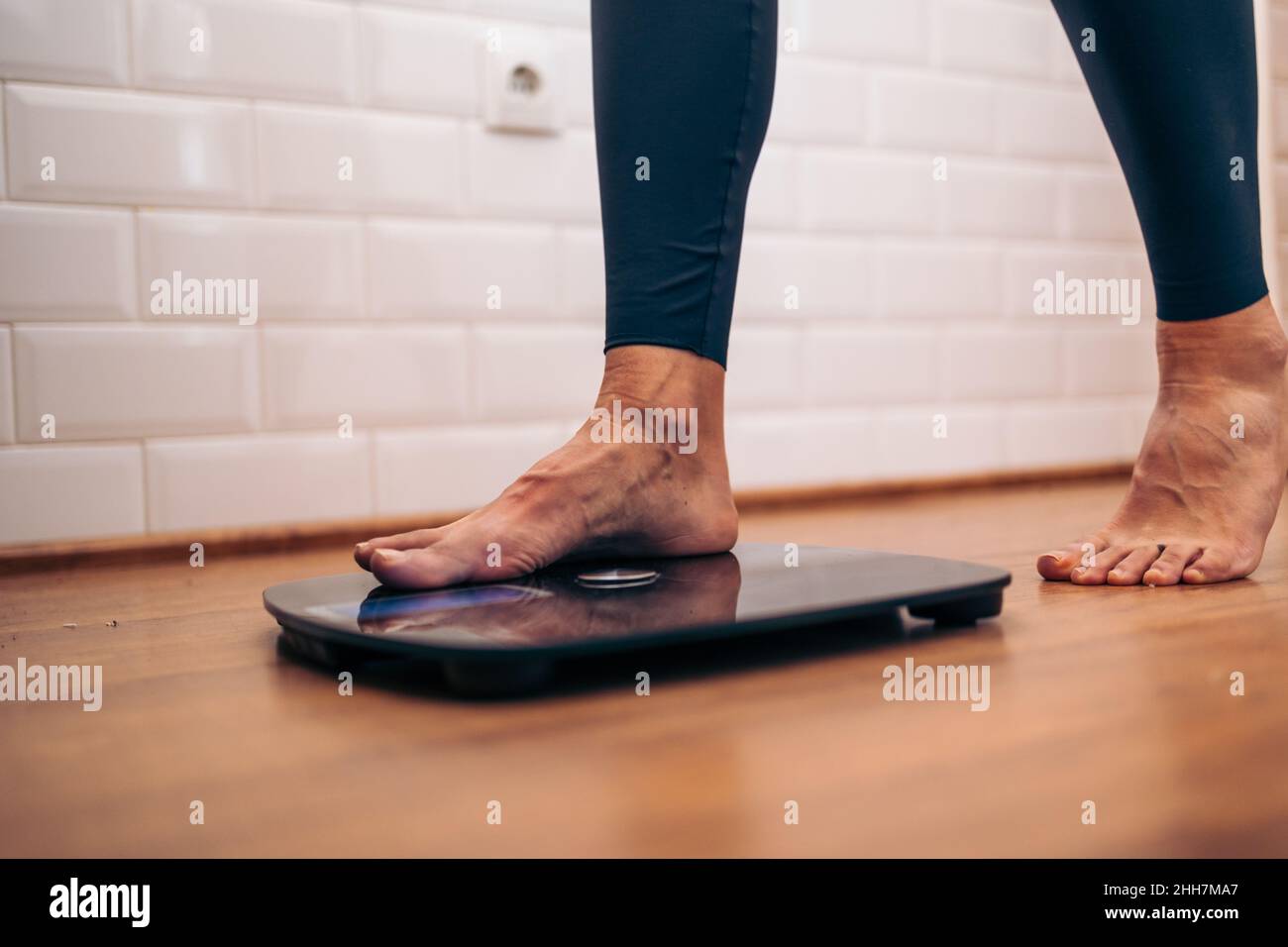 Detail of Woman getting on a bathroom scale. Diet problems concept