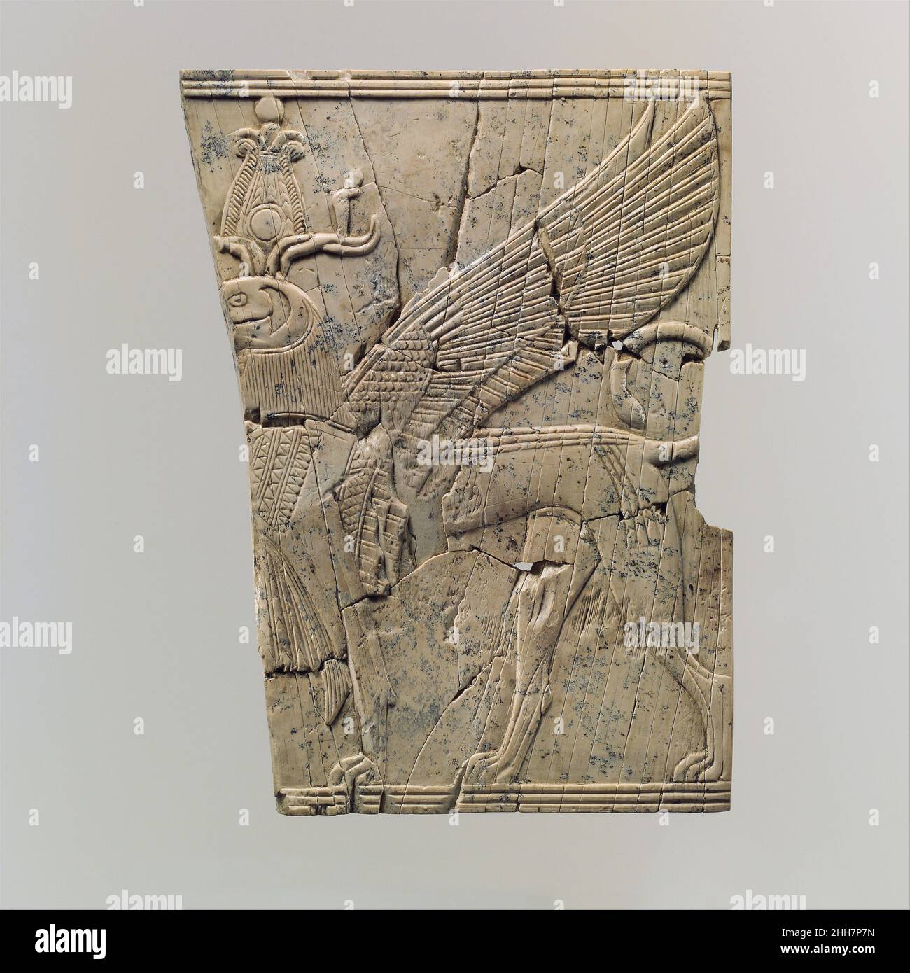 Furniture plaque carved in relief with a winged, falcon-headed sphinx ca. 9th–8th century B.C. Assyrian This exquisitely carved plaque was found in a large storeroom at Fort Shalmaneser, a royal building at Nimrud that was probably used to store tribute and booty collected by the Assyrians while on military campaign. Bound on the upper and lower edges by a border of parallel lines, a striding sphinx that combines a lion’s body with what is probably the head of a falcon is carved in very low relief. The inclusion of several Egyptian elements including the nemes cloth (a royal, pleated headdress Stock Photo