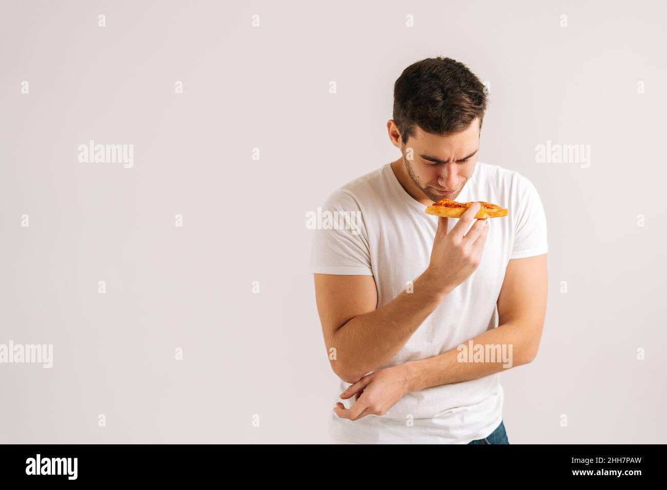 Portrait of sick upset young man feeling pain in stomach after eating pizza, suffering abdomen