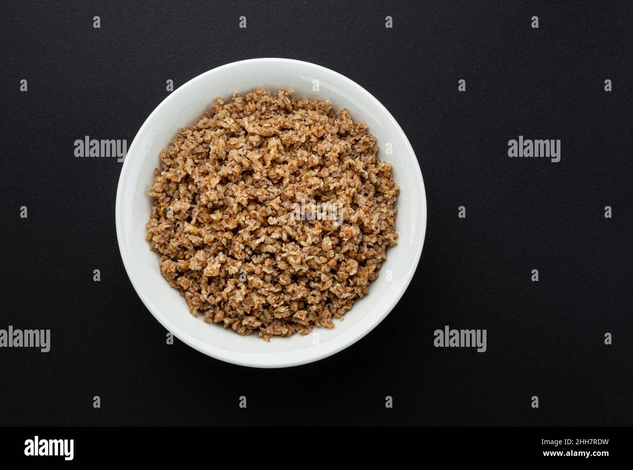 Bowl of buckwheat flakes on black background Stock Photo Alamy