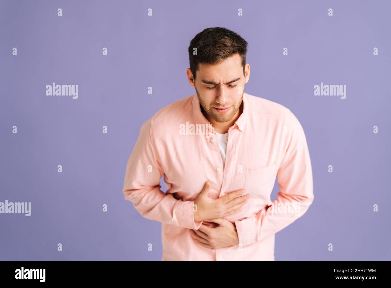 Portrait of sick young man feeling sudden stomach pain, severe