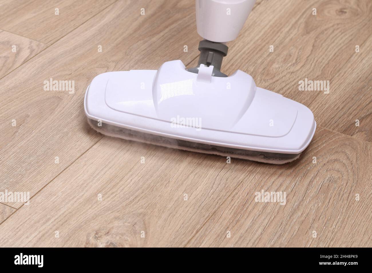 A man washes laminate flooring with a steam mop. Killing germs, clean floor, decontamination