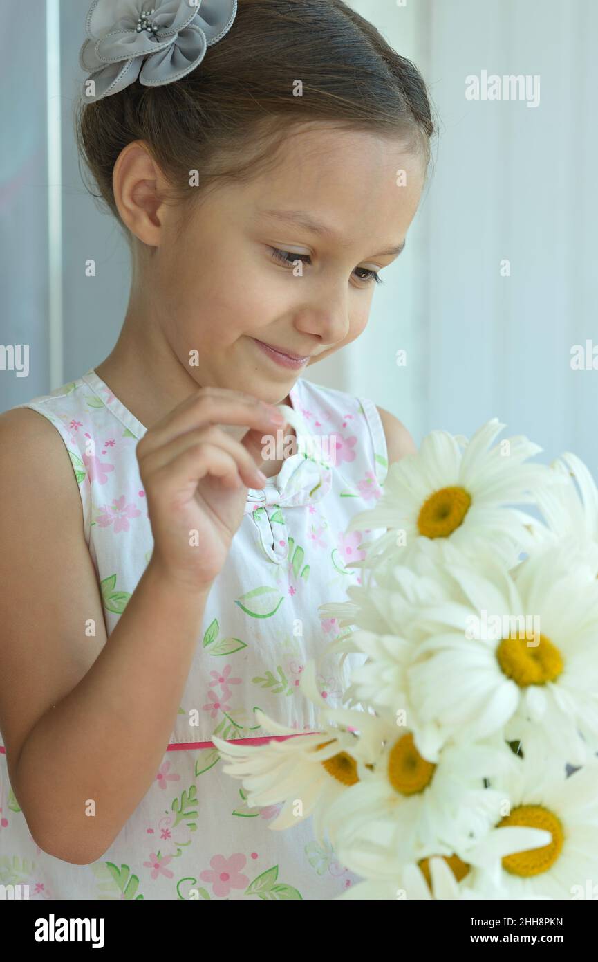 Portrait of a cute little girl at home with chamomiles Stock Photo - Alamy