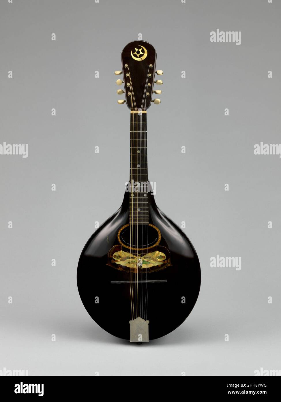 Mandolin 1898 Orville Gibson Orville Gibson is one of the most important makers and innovators of fretted stringed instruments. He is credited with the invention of the archtop guitar and mandolin, which both take construction elements from the violin. This mandolin is a rare surviving instrument by Orville Gibson and features a design consistent with his 1898 patent mandolin drawings. This includes a carved top and back with a floating bridge and tailpiece. The mandolin's sides, neck, and headstock are made from a single piece of walnut that is carved into the final form. The back is also a c Stock Photo