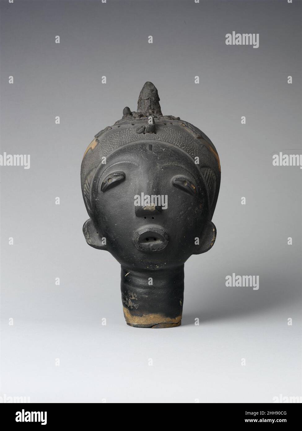 Memorial Head (Ntiri) 17th century (?) Akan peoples The Asante, Baule, and Anyi peoples belong to the Akan culture and language group. Since the second half of the sixteenth century, two traditions of terracotta sculpture produced by Akan women have played a role in funerary rites and memorialized the dead. While relief-decorated vessels are associated with the shrines of ordinary people, freestanding figures and heads were predominantly the prerogative of royalty. Enormous stylistic diversity is reflected in forms that range from seven to ten centimeters wide to lifesize and from hollow and s Stock Photo