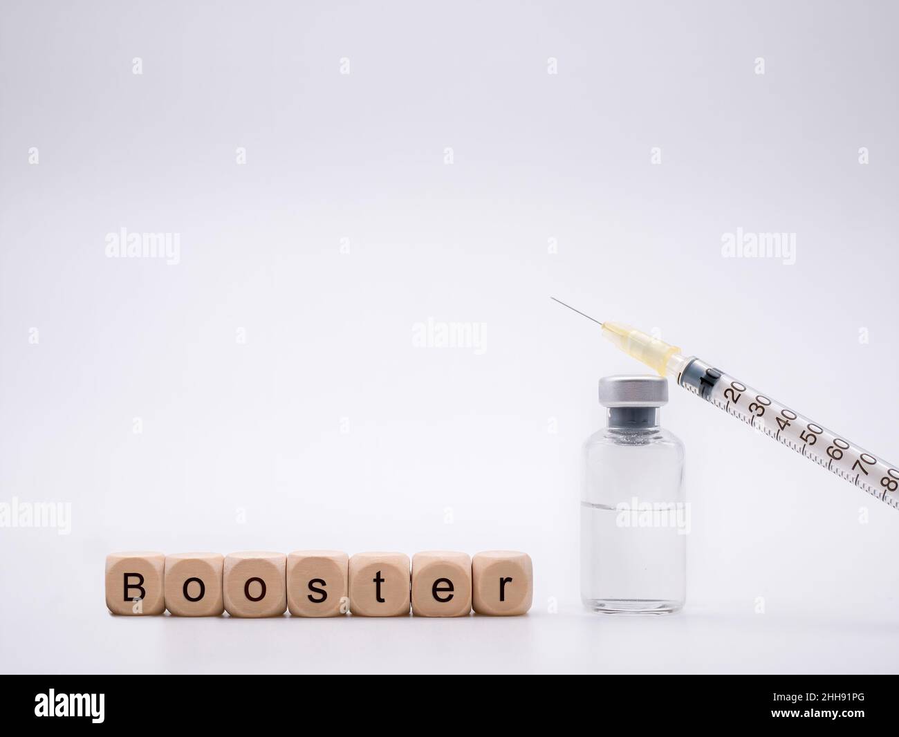 Letters 'Booster' with vaccine bottle and syringe in front of white background Stock Photo