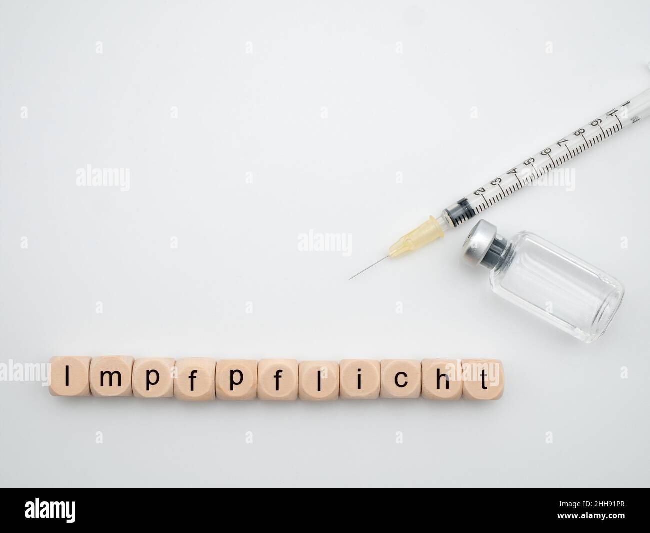 German letters 'Impfpflicht' for 'compulsory vaccination with syringe and vaccine bottle isolated on white background Stock Photo