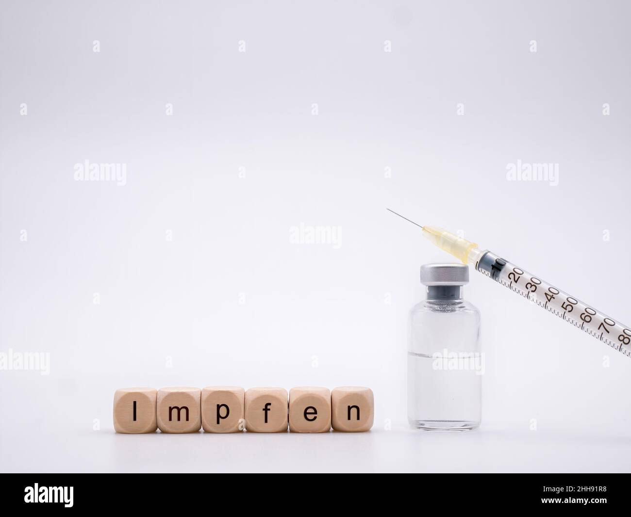 Letters 'Impfen' for German 'Vaccinate' with vaccine bottle and syringe isolated on white background Stock Photo