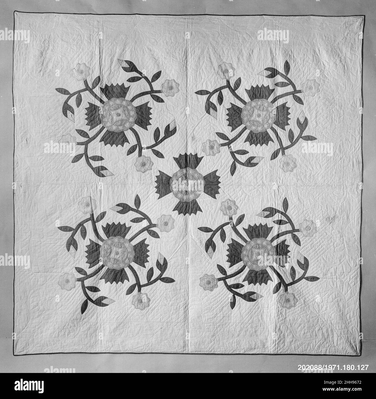 Quilt, Rose of Sharon pattern ca. 1860 American The top of the quilt is of a white cotton fabric printed with a thin red stripe. The appliquéd flowers are of pink and green cotton. The edge binding is of green plaid cotton. White cotton fabric with a small dark red figure is used for the backing. There are large-scale quilted flower and feather forms in some areas, as well as an overall pattern of diagonal parallel lines.. Quilt, Rose of Sharon pattern  13872 Stock Photo
