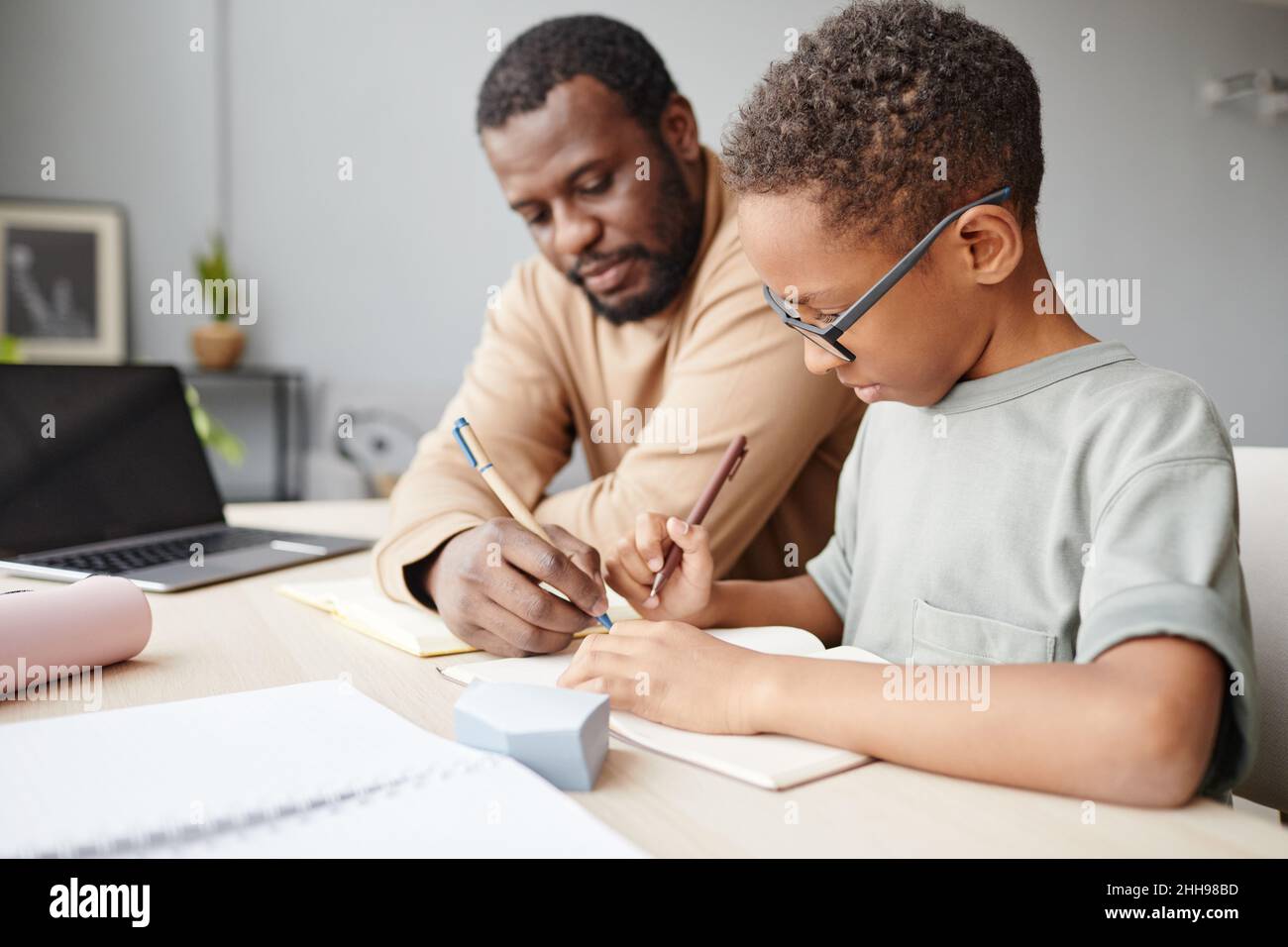 Side view portrait of African-American boy studying at home with father ...