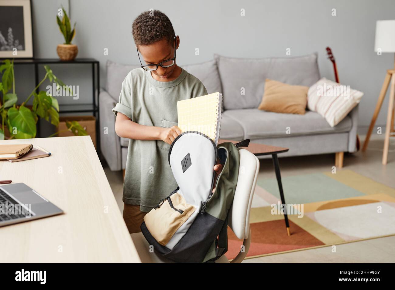 Portrait of young African-American boy packing backpack at home, copy space Stock Photo