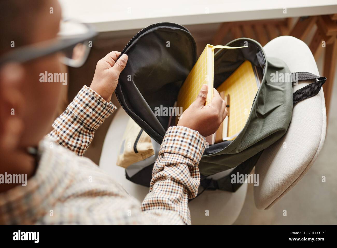 High angle close up of young African-American schoolboy packing backpack at home, copy space Stock Photo