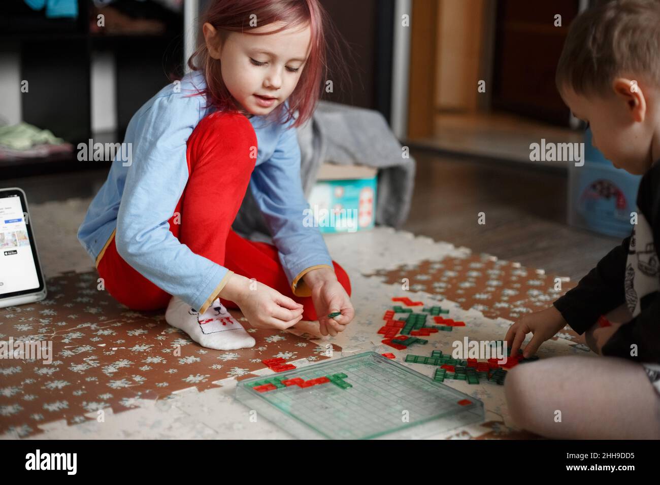 Little caucasian girl playing a board game on the floor in her room