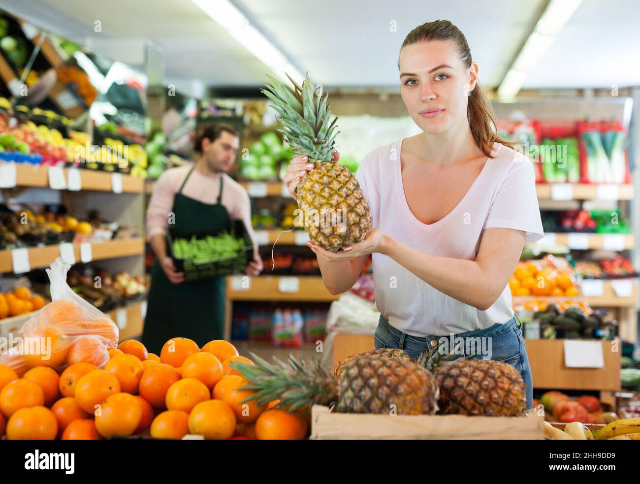 Young woman customer holding fresh pineapples in hands Stock Photo