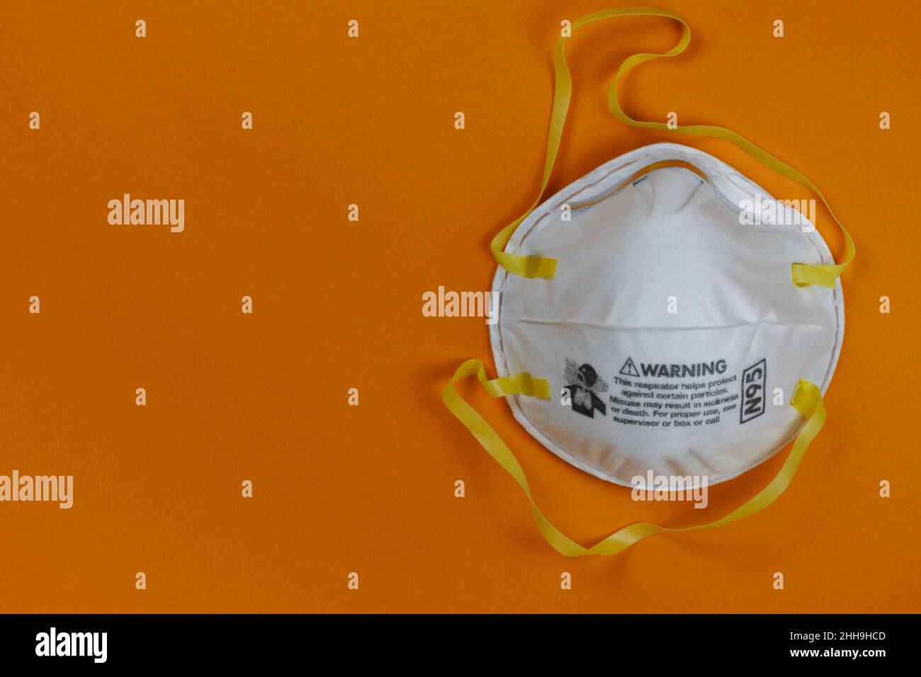 N95 face respirator face mask on a bright orange background with copy space Stock Photo