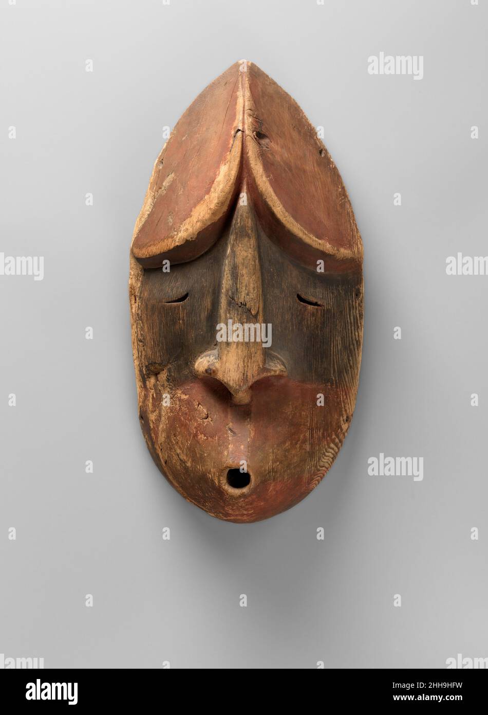 Mask ca. 1870 Alutiiq/ Sugpiaq, Native American The peoples of the Arctic region use music and performance to invoke the spirit realm. According to native Alaskan beliefs, spirits communicate with people through whistling: these masks may be the faces of such supernatural beings, as they appear to whistle at their beholders. The formal resemblance between the pair, including the prominent noses, minimal eyes, and pointed head decorations, may mark them as specific, linked characters in a myth. Early twentieth-century modernist artists and collectors were drawn to the bold simplicity of such wo Stock Photo
